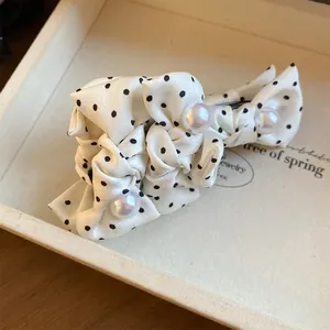 Detaillierte Nahaufnahme einer Haarspange mit weißer Polka-Dot-Stoffschleife und Perlen
