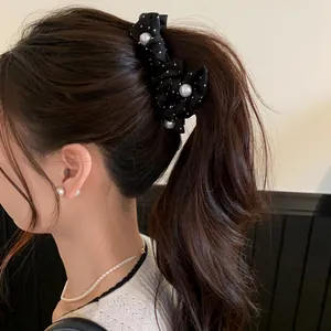 Detailansicht einer schwarzen gepunkteten Haarschleife mit Perlen an einem braunen Pferdeschwanz.