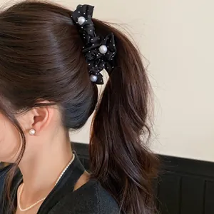 Nahaufnahme einer modischen schwarzen Stoff-Haarspange mit Polka Dots und weißen Perlen