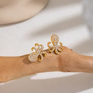 Nahaufnahme der 18K vergoldeten Oktopus-Ohrringe mit funkelndem CZ-Pavé auf Holz