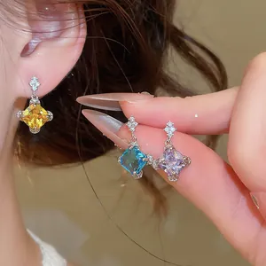 Gros plan de boucles d'oreilles pendantes étincelantes en zircone de trois couleurs