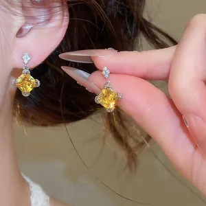 Détail de boucles d'oreilles pendantes en zircon jaune en forme de losange