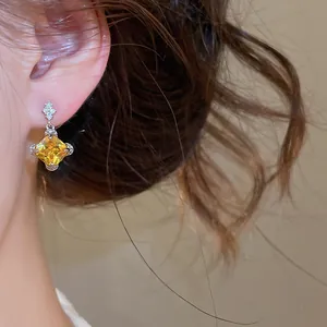 Détail de la boucle d'oreille géométrique avec zircon jaune sur l'oreille
