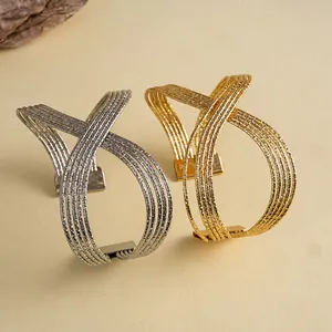 Détail de bracelets manchettes géométriques multicouches en métal plissé doré et argenté.