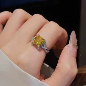 Gros plan étincelant d'une bague en zircone jaune carrée sur un doigt avec manucure rose