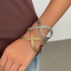 Détail de bracelets ouverts géométriques multicouches or et argent sur le poignet