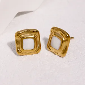Detailopname van vintage geometrische gouden oorknopjes met wit emaille inlegwerk
