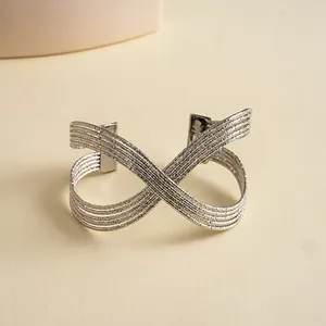 Vue macro montrant la texture plissée et le design croisé multicouche du bracelet argenté.