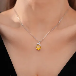 Gedetailleerd zicht van een zilveren ketting met een gele zirkoon bloemenhanger.