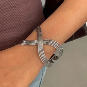 Vue rapprochée d'un bracelet manchette géométrique argenté multicouche sur un poignet féminin
