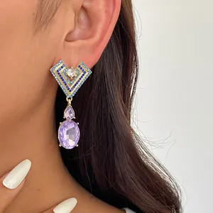 Détail de boucles d'oreilles cœur géométriques avec cristaux bleus et gemmes