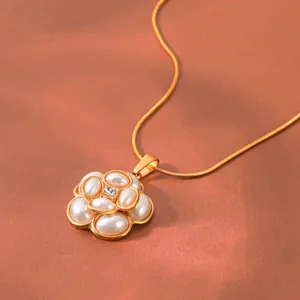 Détail d'un élégant pendentif fleur plaqué or avec perles blanches et cristal au centre.
