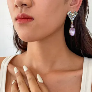 Gros plan d'une boucle d'oreille géométrique avec strass bleus et cristal violet sur mannequin