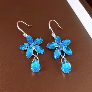 Detailed view of elegant zircon flower earrings featuring sparkling blue teardrop pendants.
