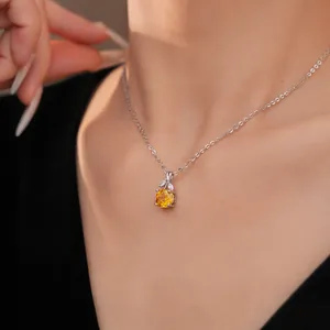 Detailopname van een zilveren ketting met gele zirkoon bloemenhanger.