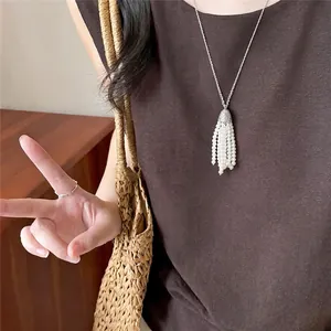 Macro view of a Korean style silver chain necklace with a white pearl tassel pendant