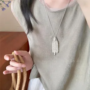 Close-up view of a Korean style pearl tassel necklace worn on a muted green top.