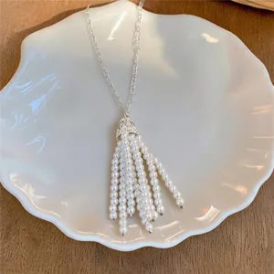 Detailed view of an elegant beaded pearl tassel necklace displayed on a shell plate