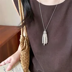 Close-up detail of an elegant beaded tassel pearl necklace worn on a brown fabric