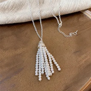 Close-up of elegant pearl tassel pendant necklace on a warm wooden background.