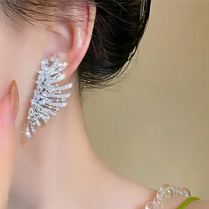 Nahaufnahme eines funkelnden Zirkon-Flügel-Ohrsteckers am Ohr für luxuriösen Look