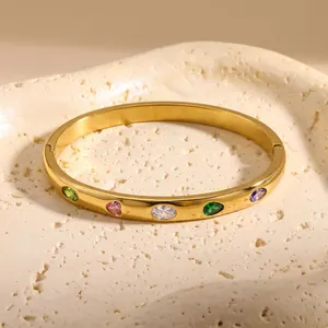 Vista dettagliata di un bracciale in acciaio dorato con zirconi colorati a forma di cuore.