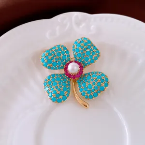 Detaillierte Makroansicht einer eleganten Vintage-Blumenbrosche mit Türkisen und Perle
