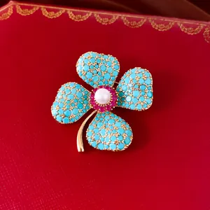 Nahaufnahme einer Vintage-Blumenbrosche mit türkisfarbenen Zirkonen und einer Perle