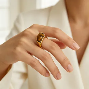 Detail eines minimalistischen Goldrings aus Edelstahl mit Tigerauge-Stein am Finger.