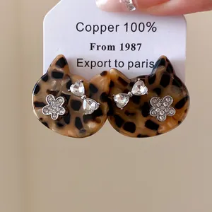Detail van luipaardprint kattenkop oorbellen met fonkelende bloemen en strik van stras
