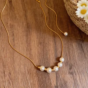 Close-up detail of an elegant 14k gold plated chain necklace featuring five white pearls