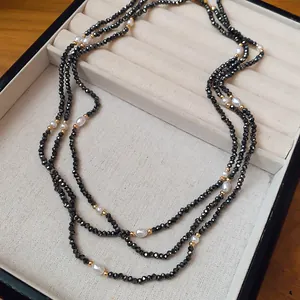 Elegantes Detail einer mehrlagigen Halskette mit schwarzen Kristallen und weißen Perlen