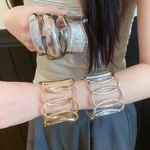 Close-up detail showing stylish gold and silver metal hollow open bangles on a model's wrist