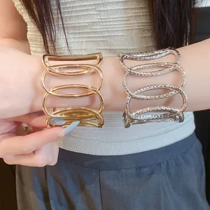 Detailed close-up showing gold and silver metal oval hollow-out open bangle bracelets