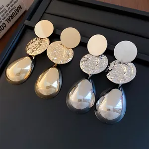 Dettaglio della trama martellata sugli orecchini a goccia d'acqua in oro e argento