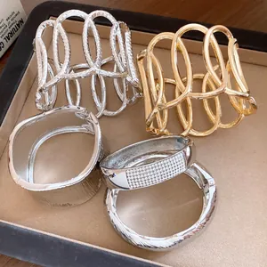 Macro view of stylish oval hollow metal bangles and rhinestone bracelets on a tray