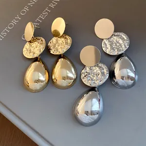 Primo piano di orecchini a goccia in oro e argento con trama martellata su un libro
