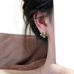 Eleganti orecchini floreali in argento con vetro verde e zircone su orecchio di modella
