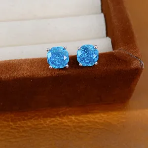 Gedetailleerde close-up van fonkelende blauwe ronde zirkoon oorknopjes in een luxe doosje