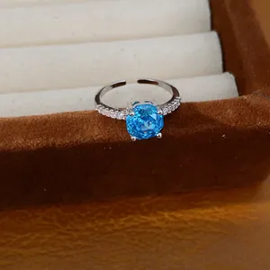 Gedetailleerde weergave van een zilveren verstelbare ring met blauwe vierkante zirkoon