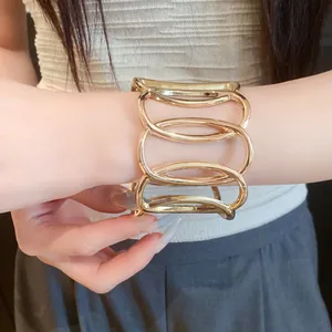 Detailed close-up view of a stylish gold-toned metallic hollow oval cuff bracelet on a wrist