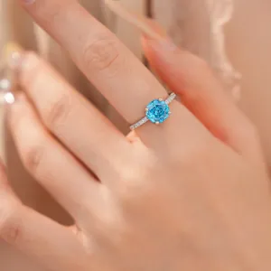 Close-up van een elegante zilveren ring met een blauwe roosvormige zirkoon op hand