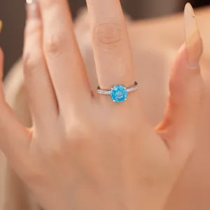 Gedetailleerd zicht op een zilveren ring met een sprankelende ronde blauwe edelsteen