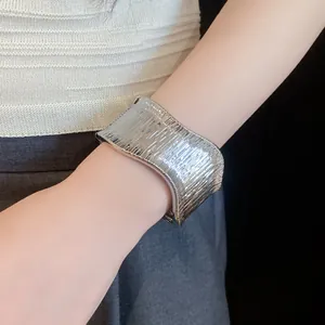 Macro view of wide silver textured metal cuff bracelet featuring a unique oval open design