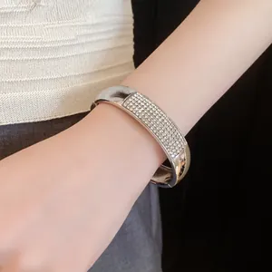 Polished silver-toned metal bangle bracelet with pavé rhinestone detail worn on a wrist