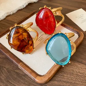 Detaillierte Ansicht von drei übergroßen Vintage-Resin-Armreifen in Bernstein, Rot und Blau.