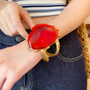 Nahaufnahme eines übergroßen goldenen Manschettenarmbands mit einem großen roten Kunstharzstein