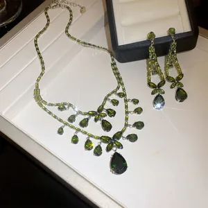 Detailansicht eines eleganten Sets aus Halskette und Ohrringen mit grünen Zirkon-Steinen