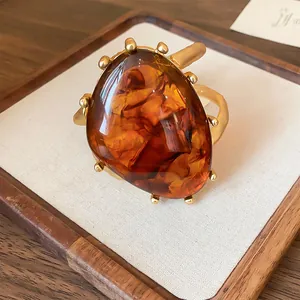 Detaillierte Nahaufnahme eines Bernsteinharz-Rings mit Goldrahmen auf einem Polster