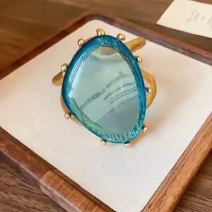 Detailansicht eines goldfarbenen Manschettenarmbands mit großem blauem Kunstharzstein.
